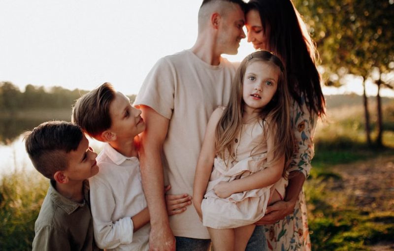 Family enjoying quality time together outdoors by the lake during sunset.